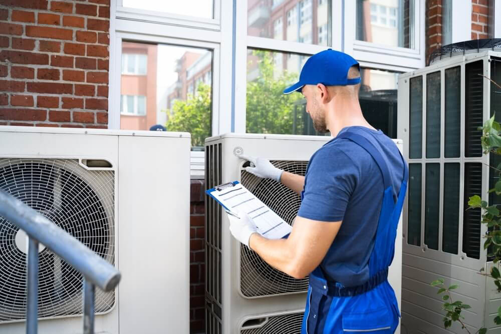 HVAC technician checking air conditioner - The ultimate HVAC maintenance checklist for techs